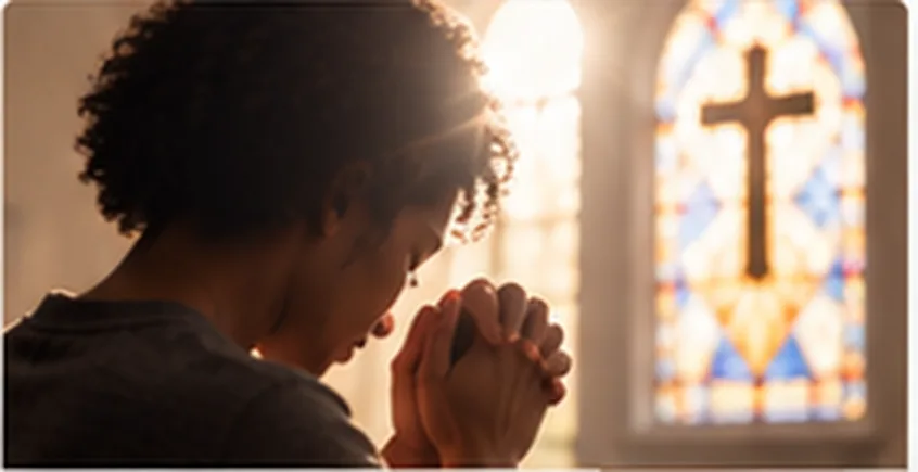 Person praying in church with cross in stained-glass light